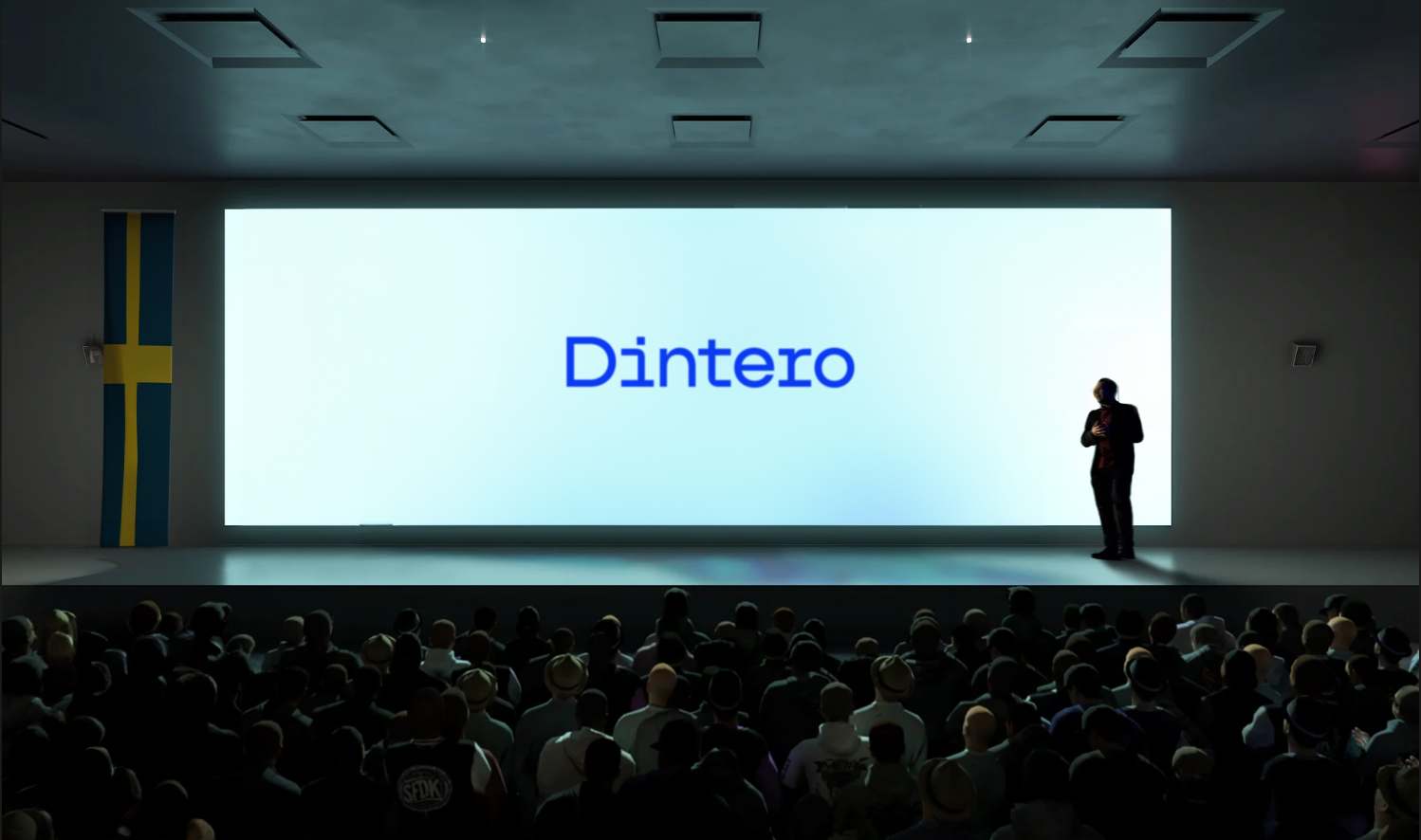 A stage in a dark auditorium with a wide screen on the stage showing the Dintero logo